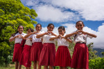 Tyttökoululaisia Indonesiasta punaisissa hameissa ja valkoisissa paidoissa, tekevät käsillään sydämen muodon